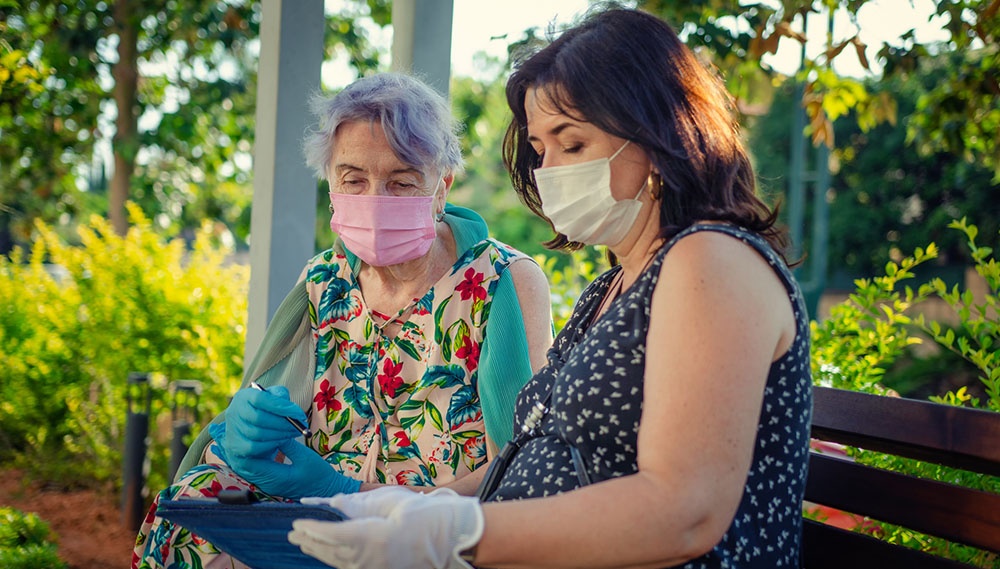 Two woman on a bench looking at an ipad